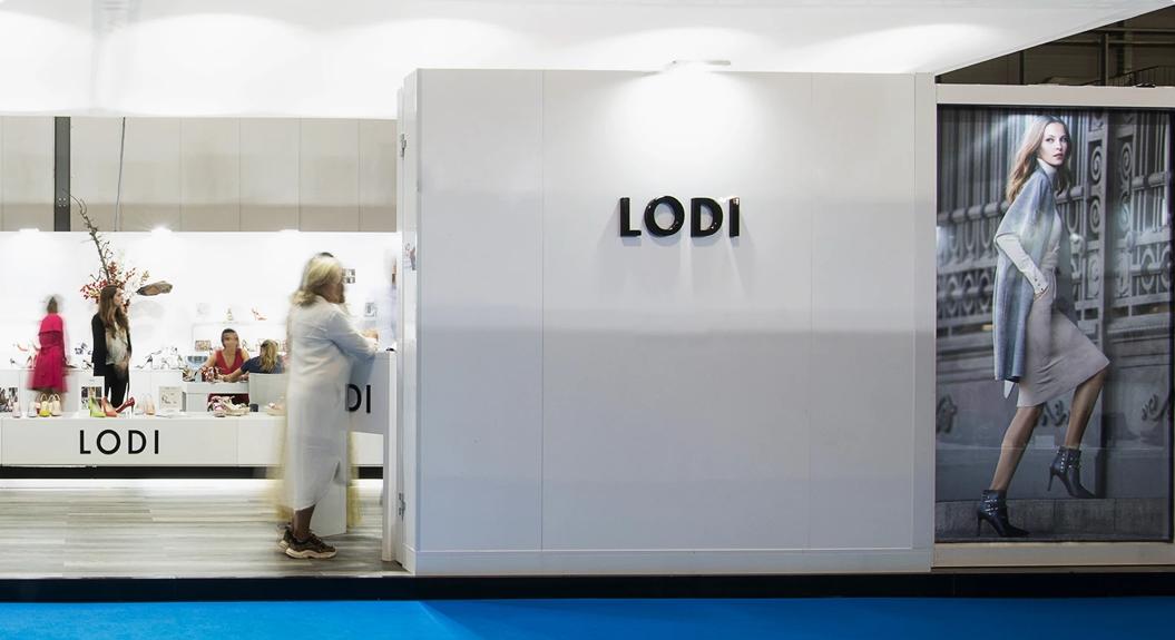 Stand LODI con parete bianca, logo 3D e vetrina calzature