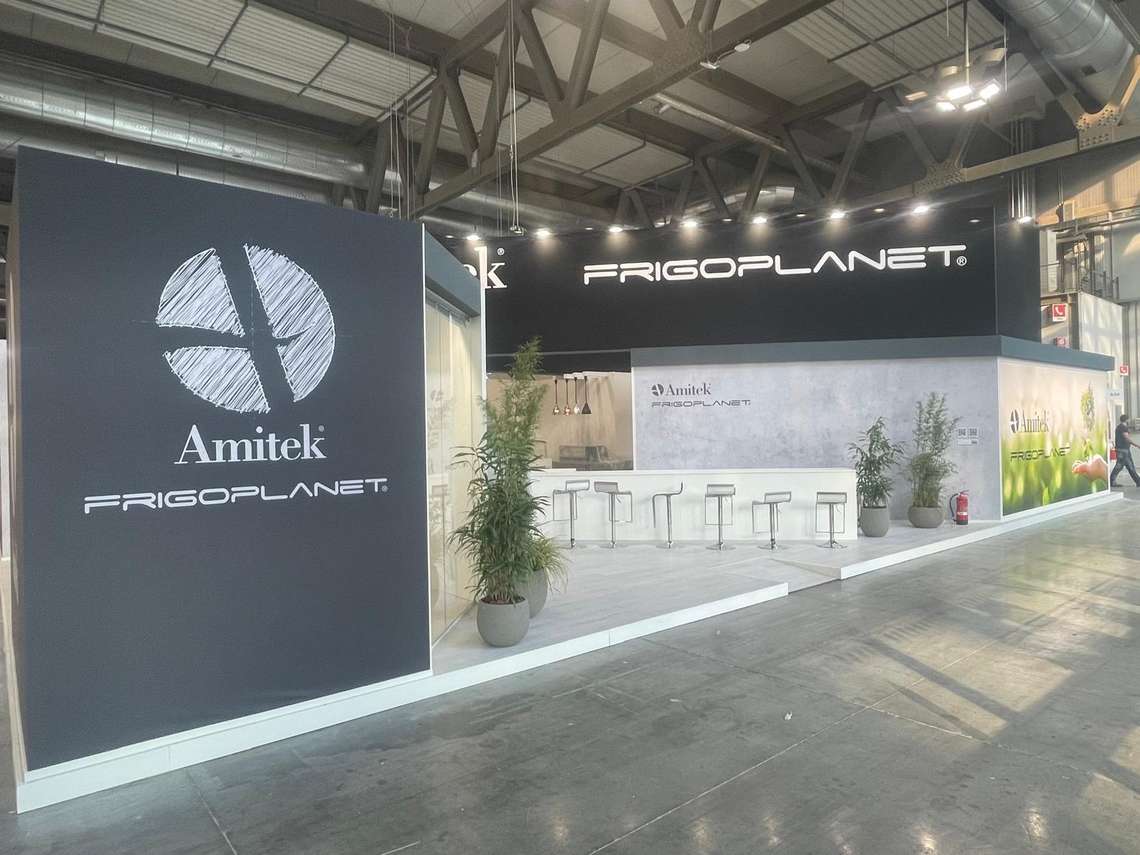 Stand FRIGOPLANET con parete grigia, bancone bianco e piante di bambù